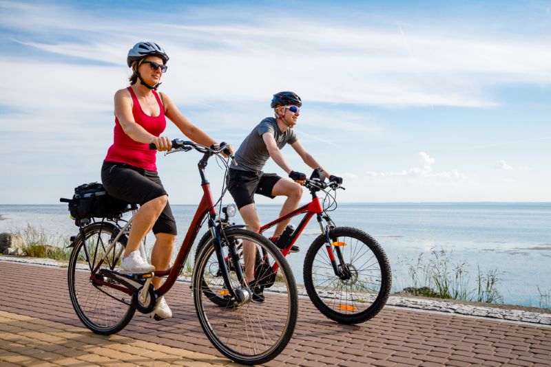 older couple cycling by the water