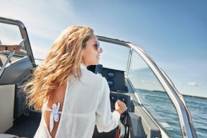 woman smiling and wearing sunglasses driving a boat