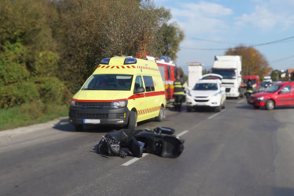 fallen motorcycle in the foreground, with an ambulance
