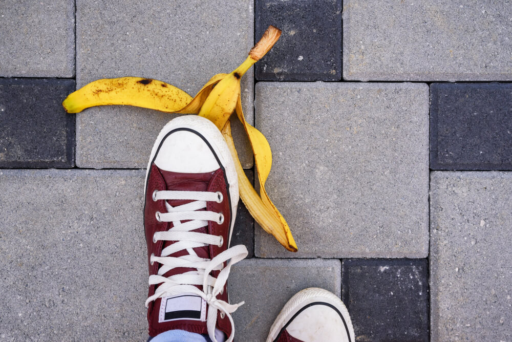 a person about to step on a banana peel lying on a paved walkway