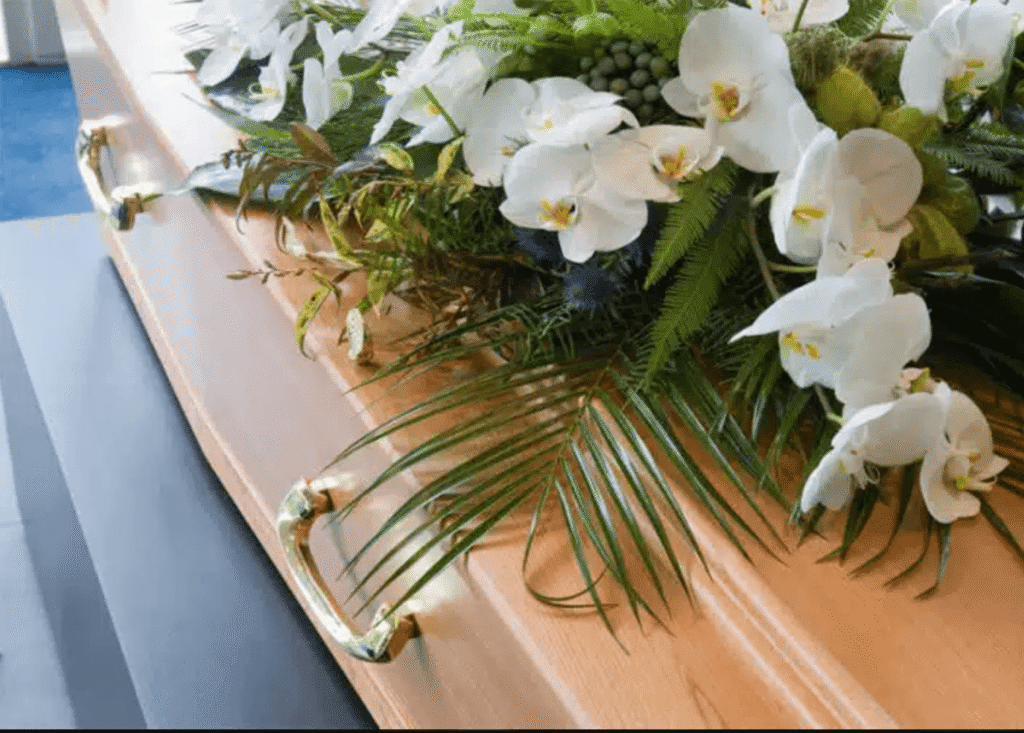 arrangement of white orchids and green foliage in a funeral