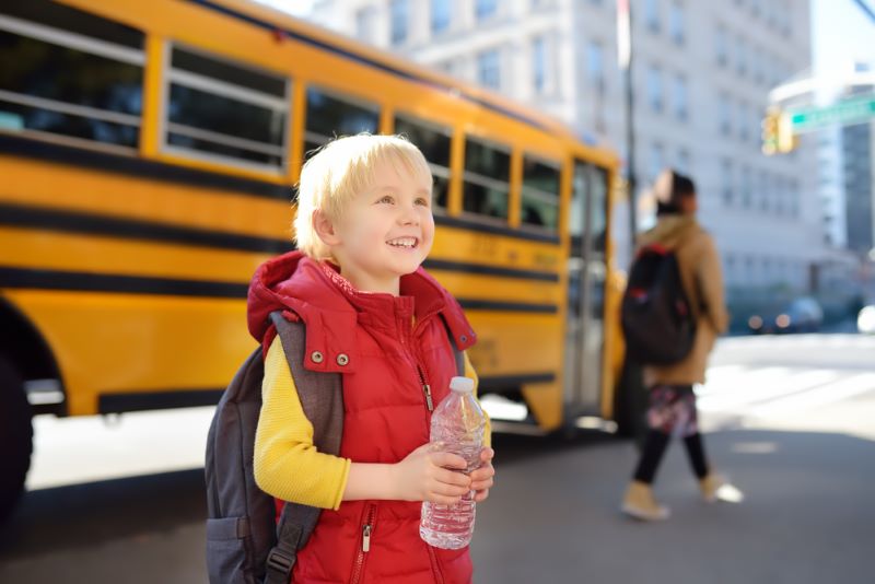 little boy getting off of school bus