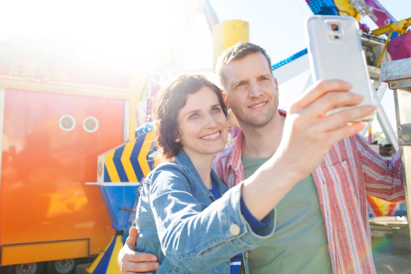 couple smiling and taking a selfie at an amusement park