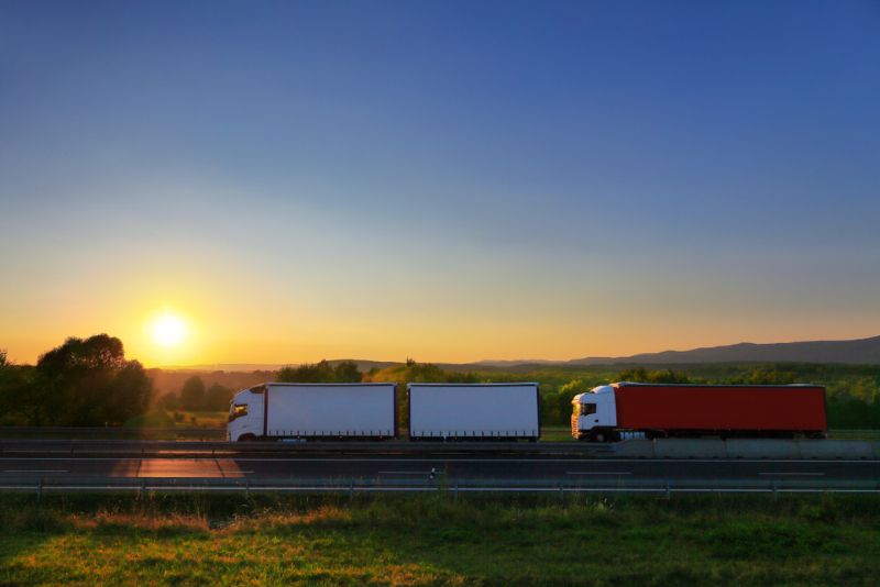 two semi trucks on the highway at sunset