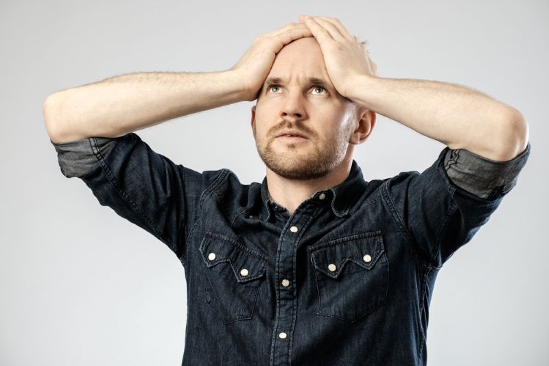 Anxious and overwhelmed man holding his head