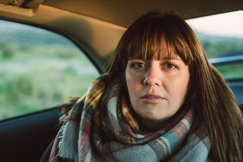 concerned looking woman sitting in the back seat of a car