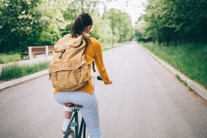 Woman riding her bike to school with backpack on