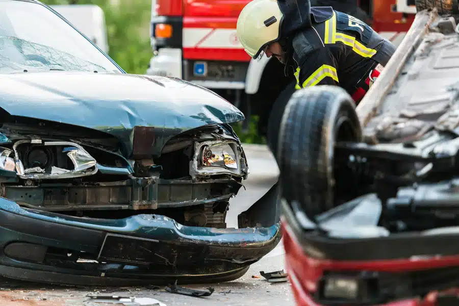Firefighter inspecting damage at the scene of a two-car accident