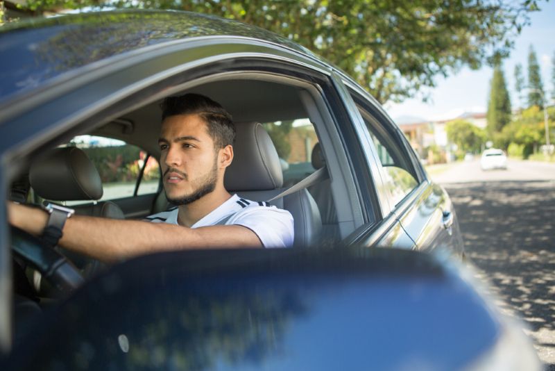 A man driving his car during the day