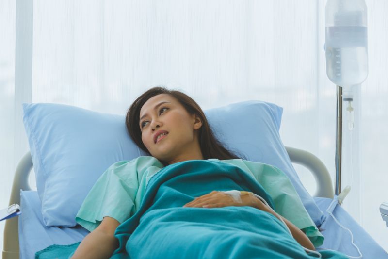 A woman lying still in a hospital bed