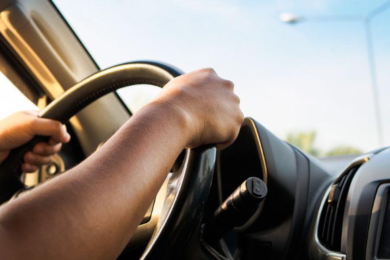 Two hands firmly grasping car steering wheel